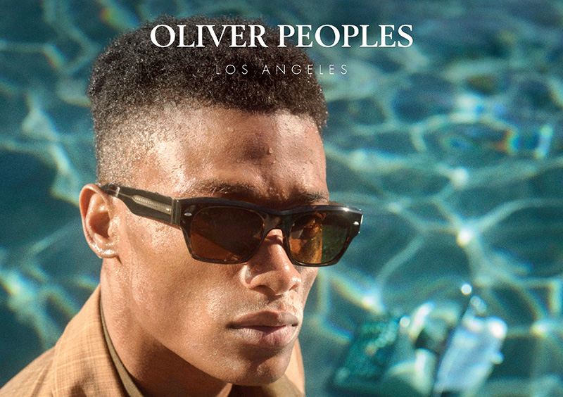 Mann mit dunkler Oliver Peoples Sonnenbrille vor Wasser