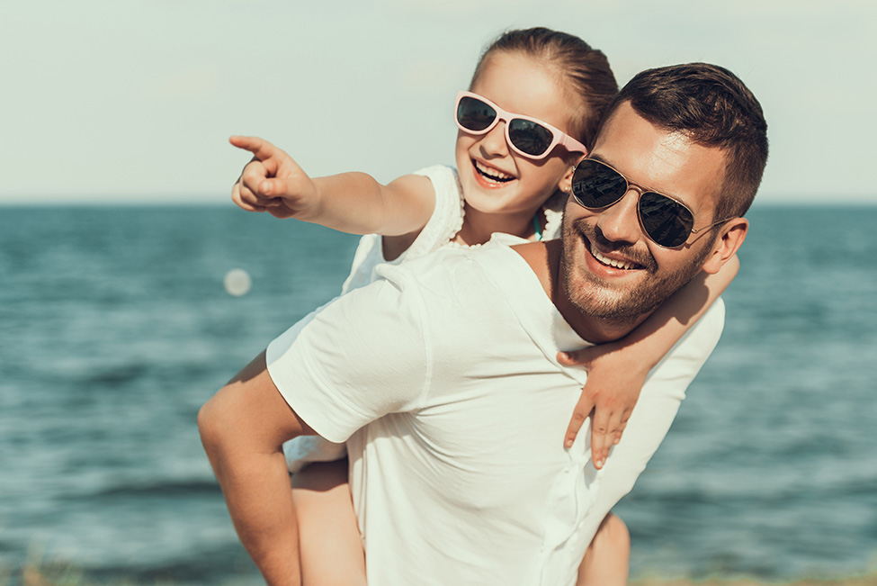Vater und Tochter mit Sonnenbrillen am Meer