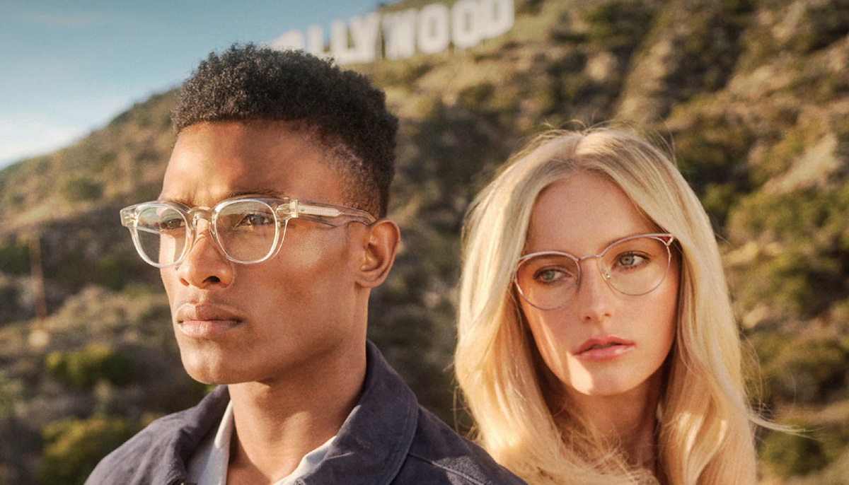 Mann und Frau vor dem Hollywood Schriftzug mit Oliver Peoples Brillen